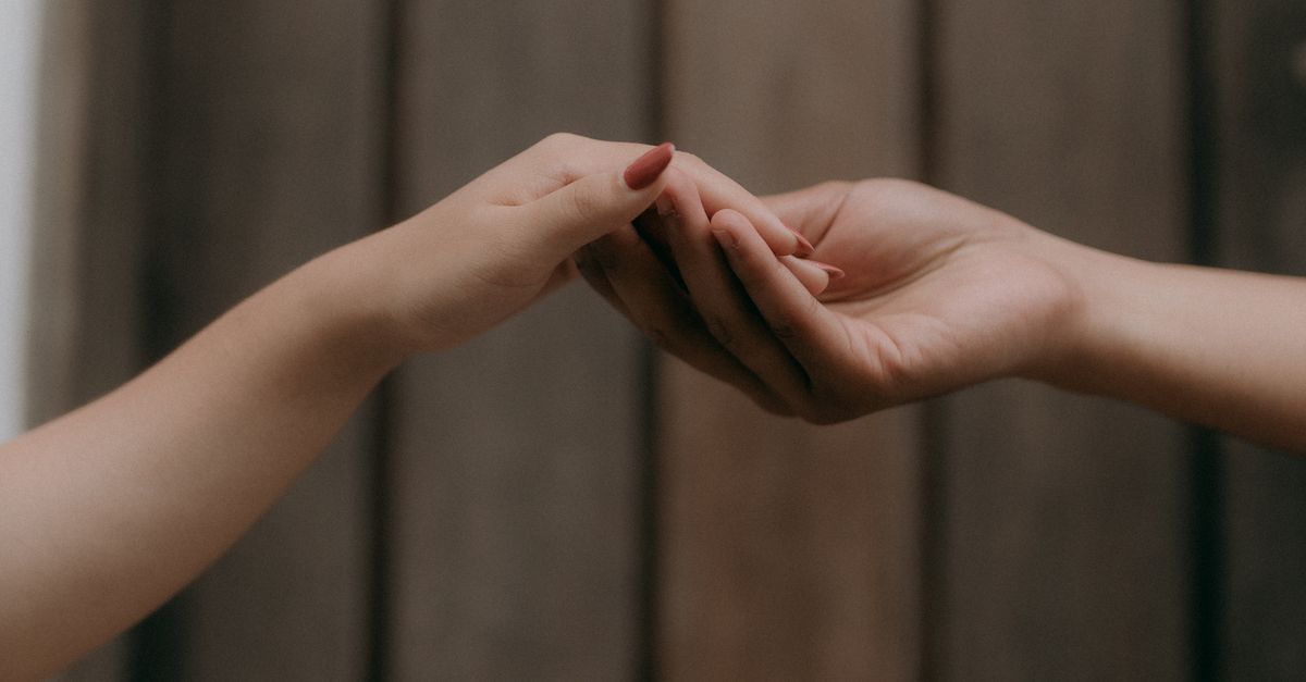 Rüyada Başkasının Aşkını İtiraf Etmesi - Rüya Tabiri ve Anlamı - Minimalist image of two hands softly reaching out to each other against a wooden background.