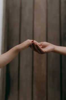 Minimalist image of two hands softly reaching out to each other against a wooden background.