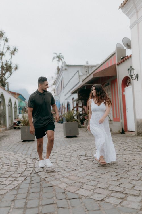 Free Happy couple strolling along a cobblestone path in a vibrant historic neighborhood. Stock Photo