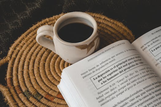 An open book and coffee cup on a rustic woven mat create a warm, cozy reading setting.