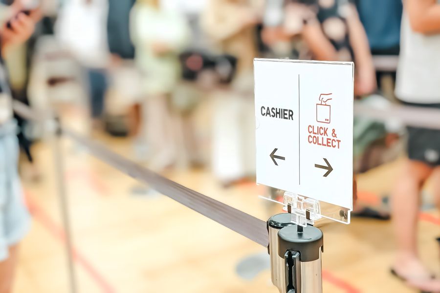 Blurred indoor scene showing a queue with a click and collect sign.