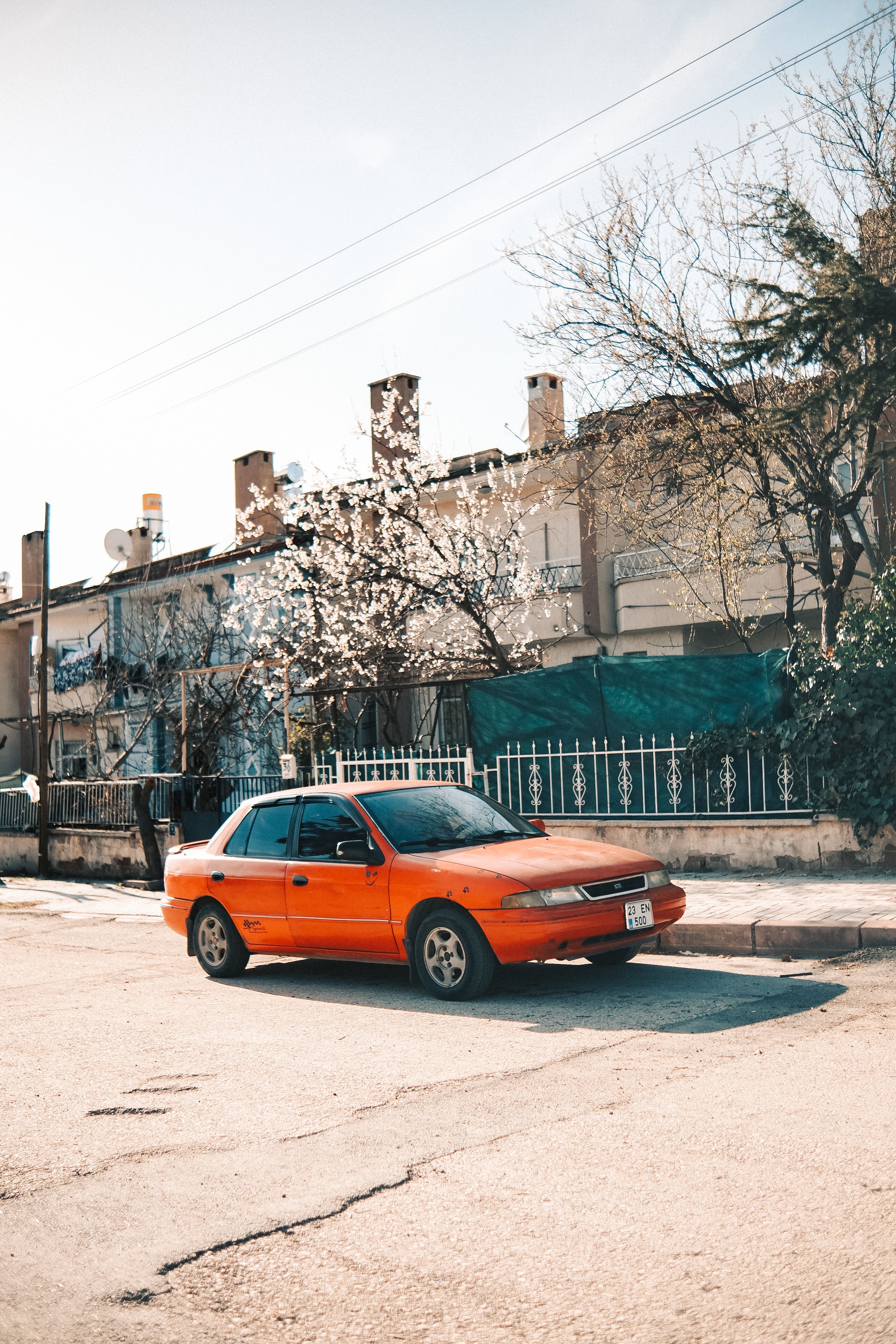 Sunny Urban Street with Parked Red Car · Free Stock Photo