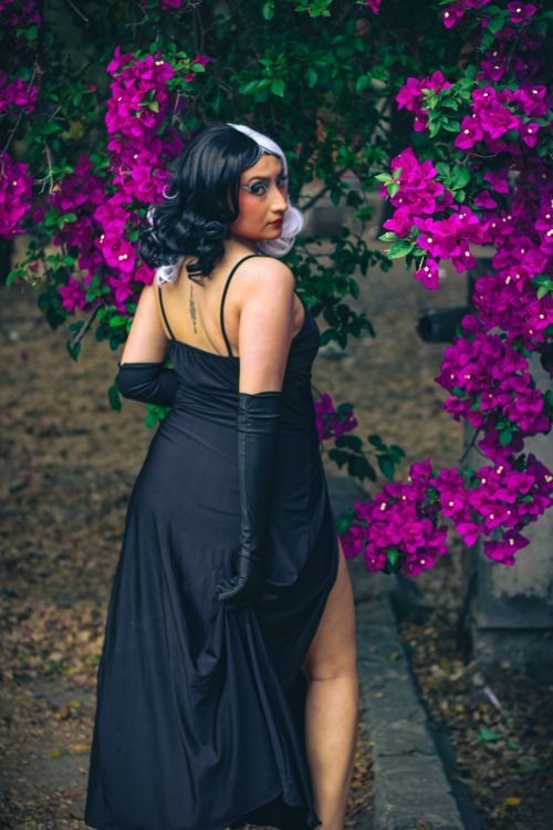Free A woman in a black dress poses gracefully amidst vibrant bougainvillea flowers in a park. Stock Photo