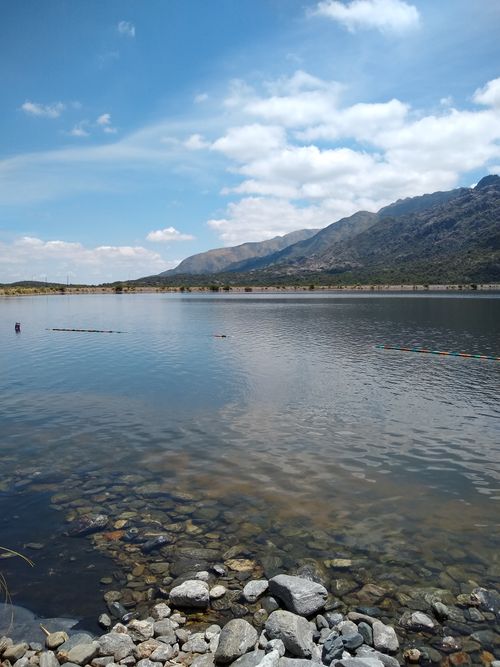 Free Tranquil mountain lake with clear blue sky and rocky shoreline, perfect for nature lovers. Stock Photo