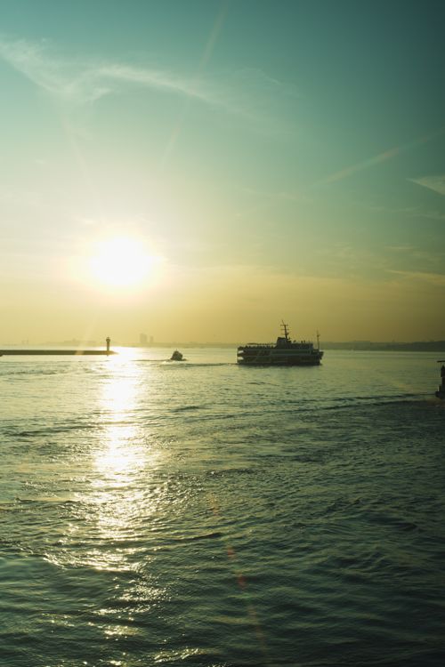 Free Serene sunset scene over a river with a ferryboat casting reflections. Stock Photo
