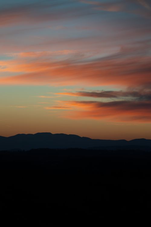 Free A tranquil sunset scene with colorful skies and mountain silhouettes, ideal for backgrounds. Stock Photo