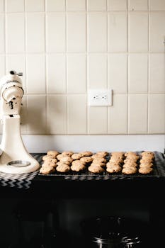 Modern kitchen with freshly baked cookies on a cooling rack, showcasing culinary warmth.