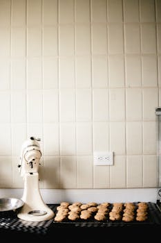 A modern kitchen counter with freshly baked cookies and a stand mixer.