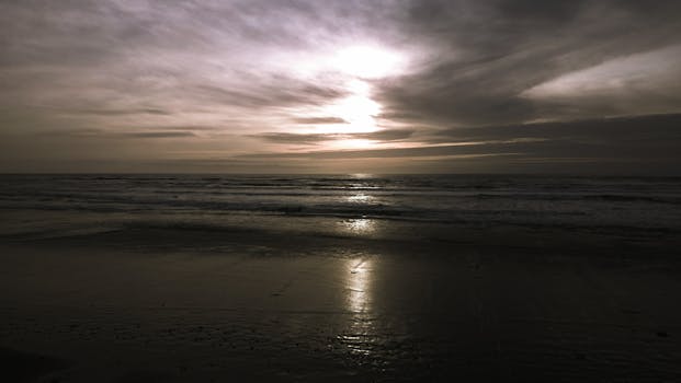 A dramatic sunset over the ocean with reflective light on the water.