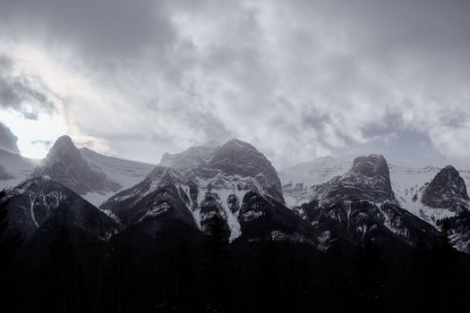 Majestic winter mountains under a cloudy sky in a dramatic setting.