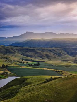 Majestic view of the Drakensberg mountains at sunrise, showcasing lush green valleys.
