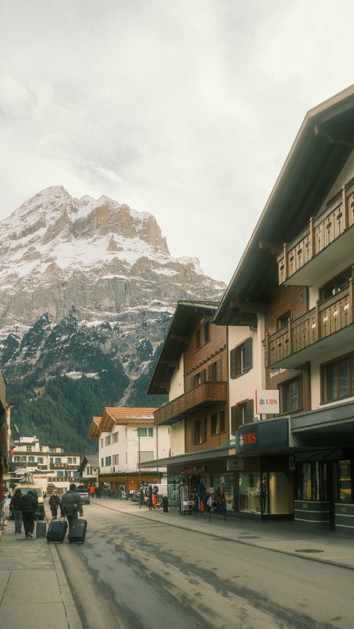 Free Idyllic street view in an Alpine village with stunning snow-capped mountains. Stock Photo