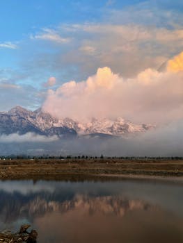 Breathtaking view of snowy mountains and serene lake reflection at sunset in Lijiang, China.