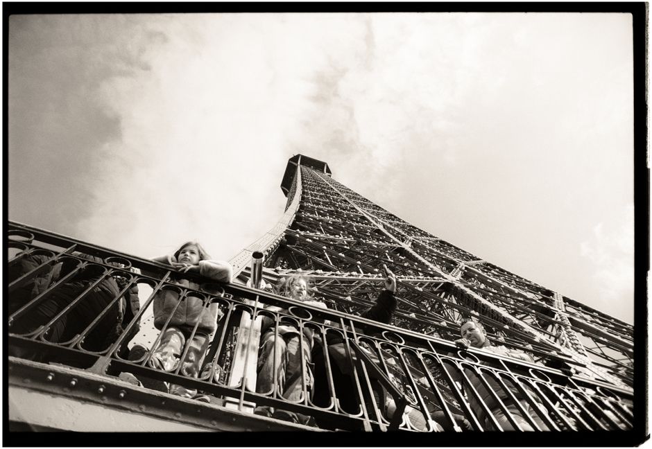 A view from below the Eiffel Tower capturing visitors in black and white.