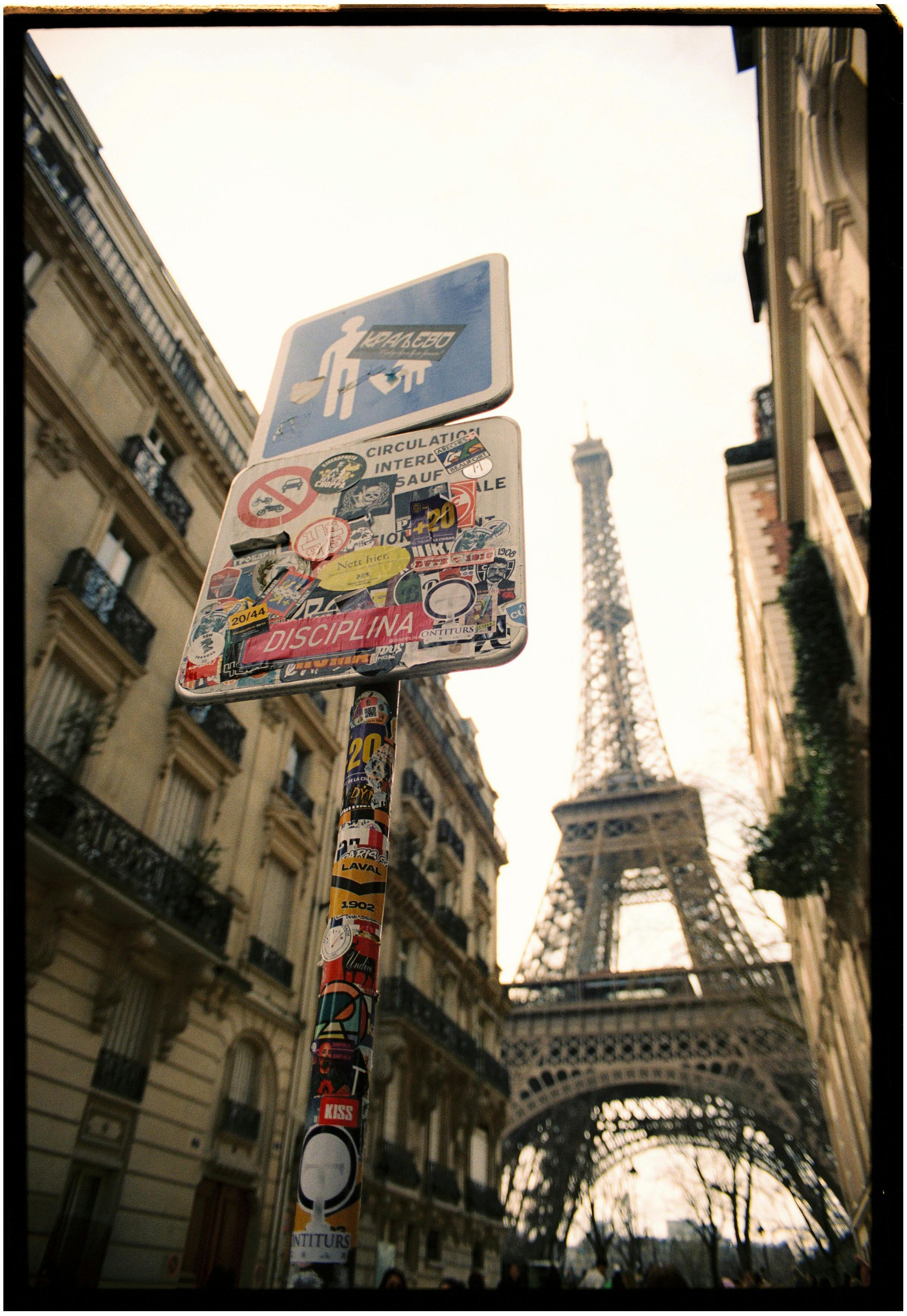 Street view of Eiffel Tower with unique urban signs and Paris architecture.