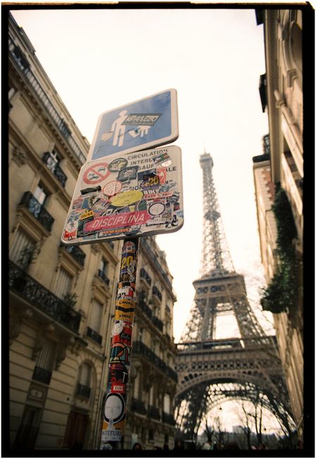 Street view of Eiffel Tower with unique urban signs and Paris architecture.