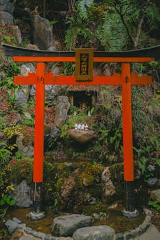 Enchanting red torii gate in a lush Japanese forest setting, showcasing cultural heritage.