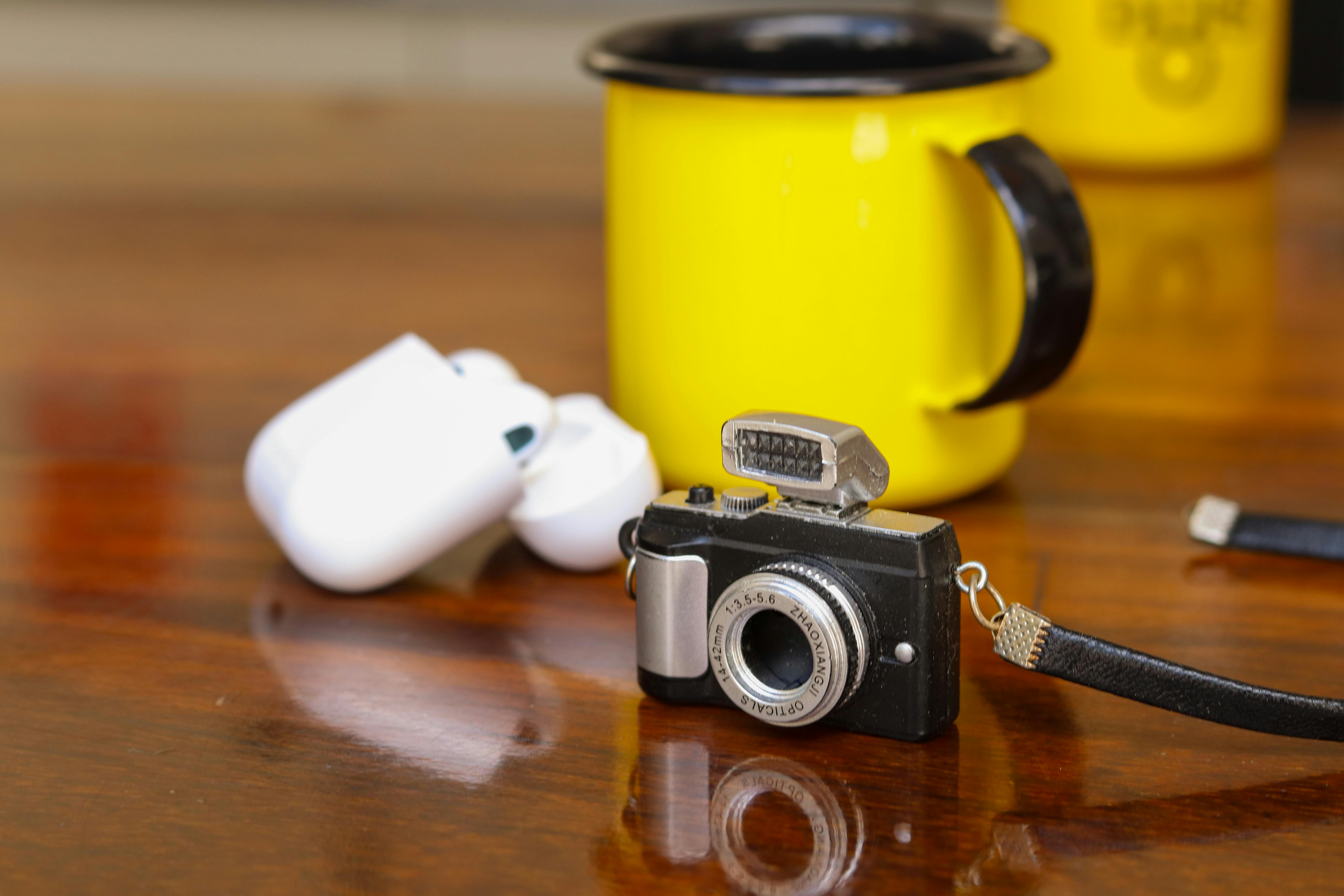 https://www.pexels.com/photo/miniature-camera-with-airpods-and-mug-on-table-31317034/