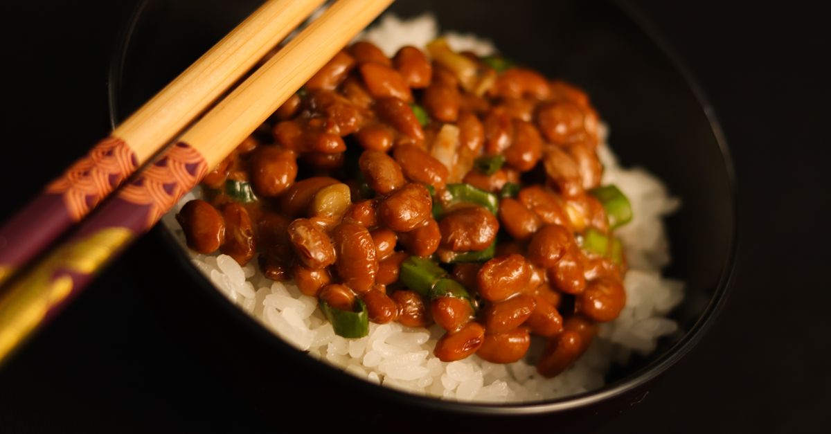 A bowl of natto beans served over white rice with chopsticks on a dark background. - Evidence evidence guide for rice protein muscle randomized trial