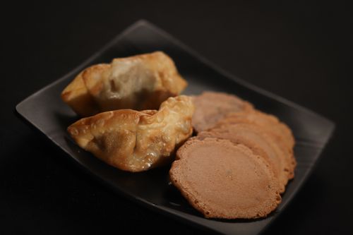 Free A close-up of fried dumplings and cookies on a black plate, perfect for culinary themes. Stock Photo