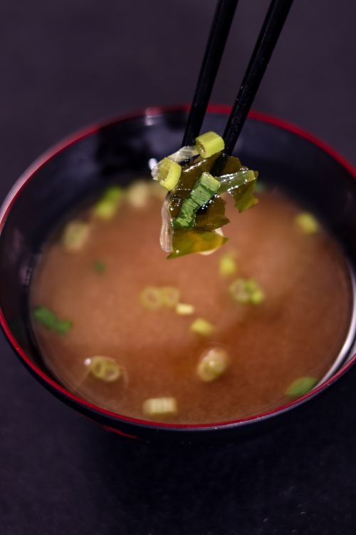 Free Close-up of traditional miso soup with seaweed and scallions in a black and red bowl. Stock Photo