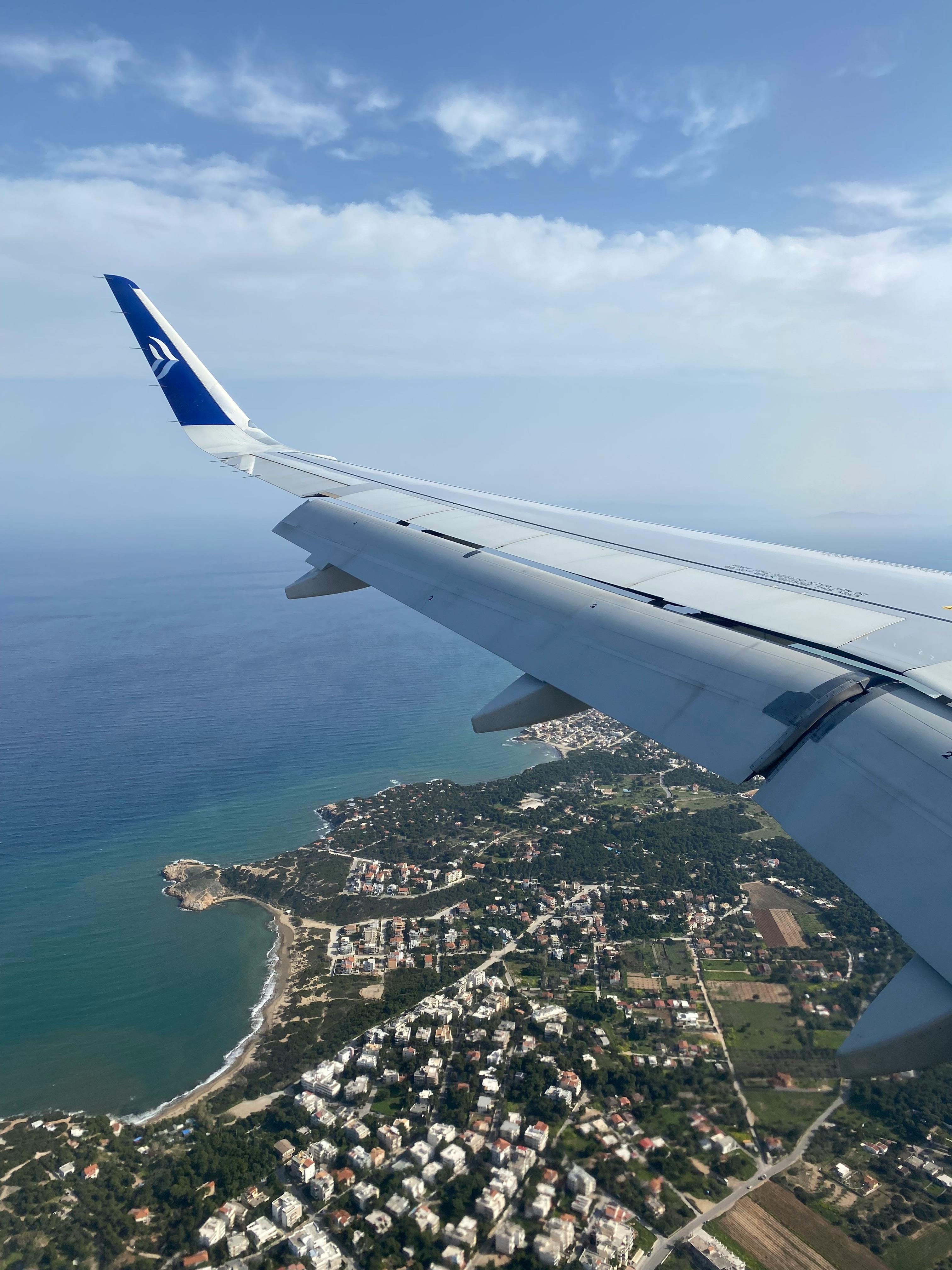 A stunning aerial view of the coastline and ocean seen from an airplane window, showcasing breathtaking scenery.