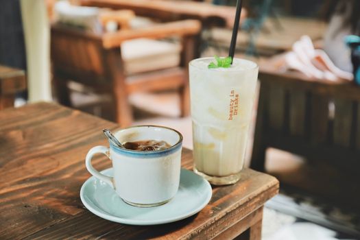 A cozy scene with coffee and iced drink on a wooden table at a cafe.