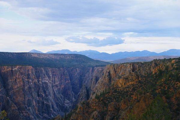 Black Canyon of the Gunnison with mountains on the horizon, the kind of Colorado landscape that draws people moving to Colorado