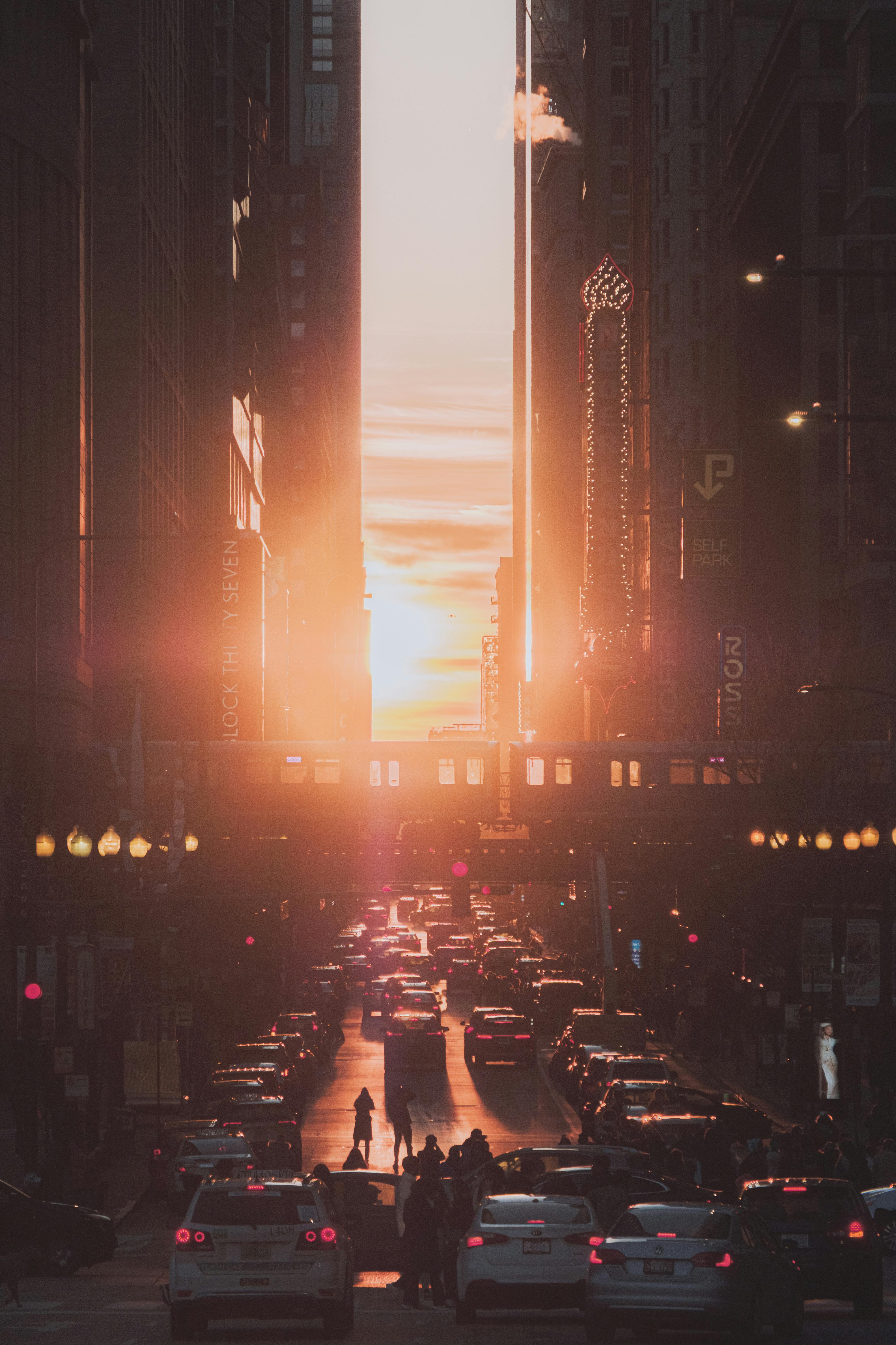 Silhouette of people and cars during sunset on a busy Chicago street, creating a vibrant urban atmosphere.