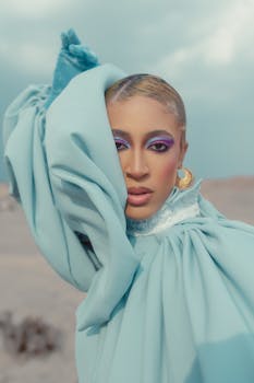 Striking portrait of a woman with elaborate makeup and blue attire against a desert backdrop.