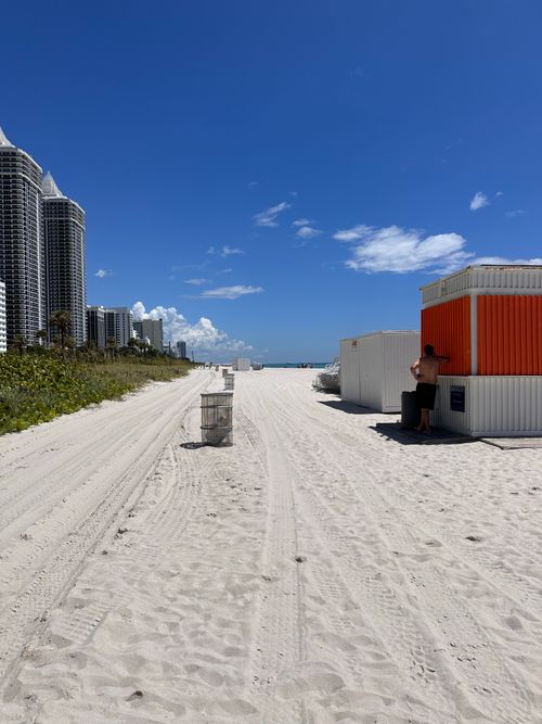 Free A serene Miami Beach scene with clear skies, skyscrapers, and a beach hut. Stock Photo