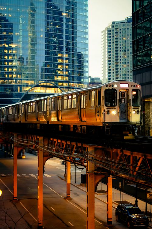 Free A modern train on elevated tracks in an urban setting during twilight with skyscrapers in the background. Stock Photo
