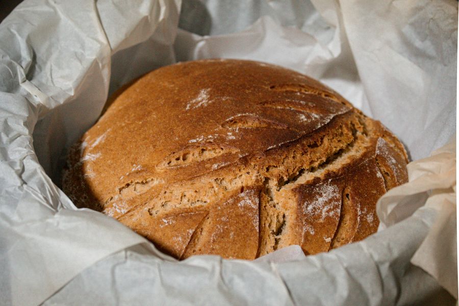 A loaf of artisanal wholegrain bread, freshly baked and wrapped in parchment paper.