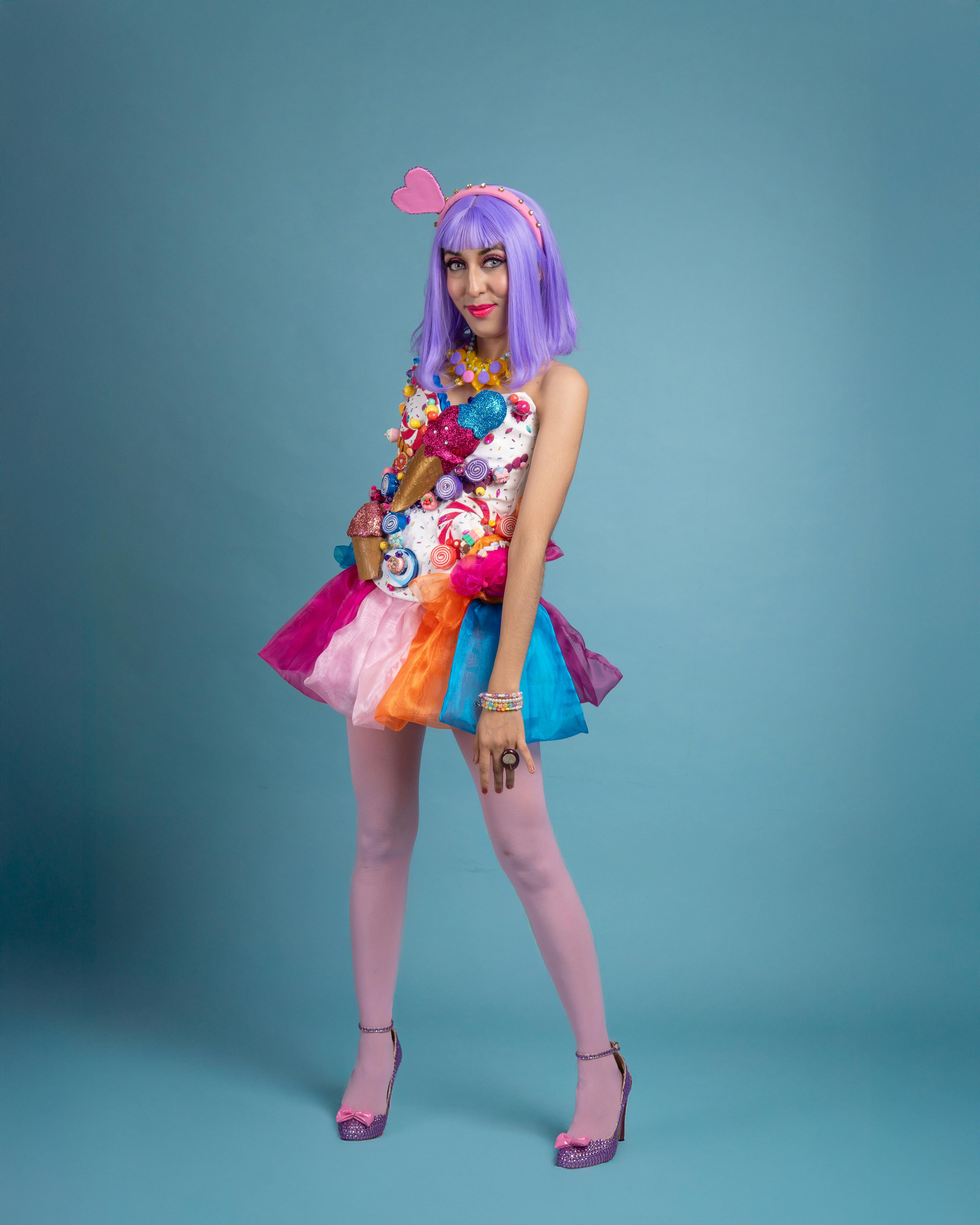 ingyenes Élénk cosplay fotó színes cukorka témájú ruhával és lila parókával kék háttéren. Stockfotó