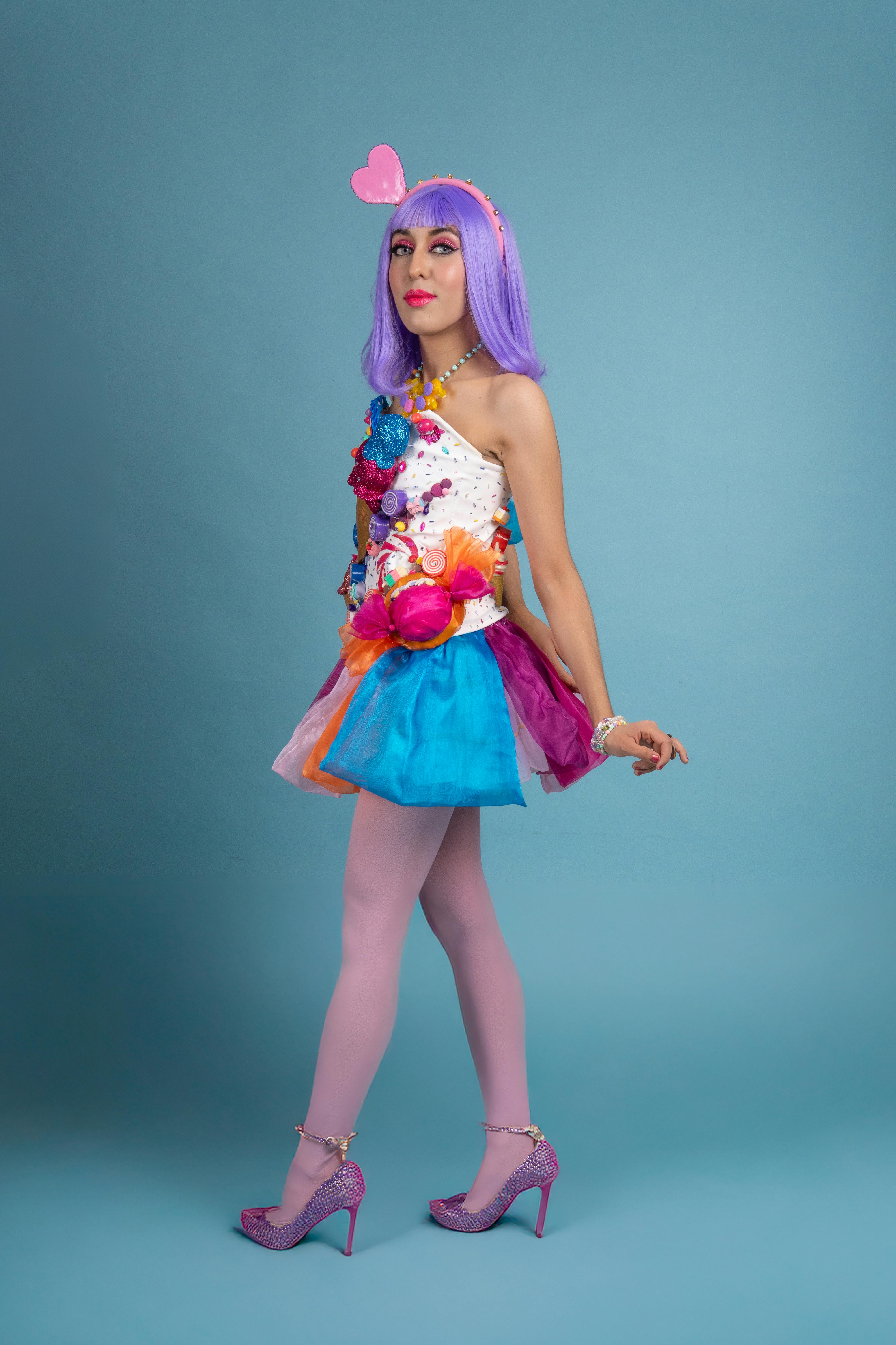 ingyenes Fiatal nő színes cosplayben, lila parókával, kék háttérrel, élénk divatot és kreativitást megtestesítő. Stockfotó