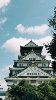 A stunning view of Osaka Castle with blue skies and lush greenery surrounding it.