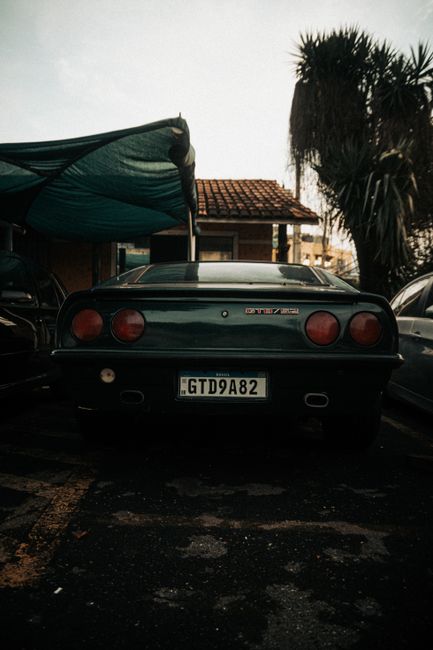 Fotomural Vista trasera de un automóvil clásico antiguo estacionado al aire libre bajo un toldo, mostrando su diseño y color icónicos.