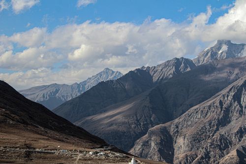 Free Stunning mountain landscape with rugged peaks under a vibrant blue sky and scattered clouds. Stock Photo