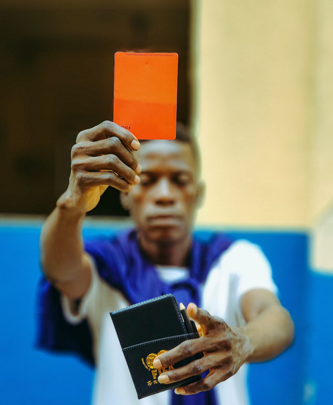 Focus on a man holding a red card and a wallet, symbolizing penalty or warning.