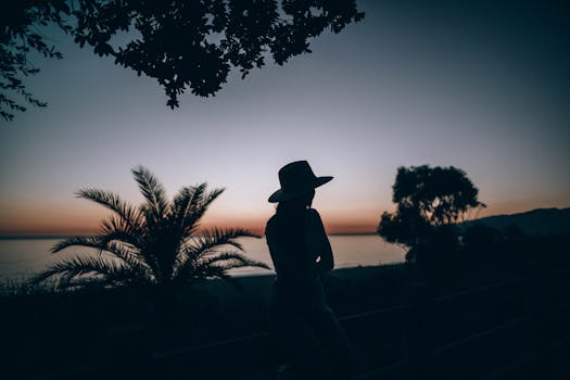 日落时分，海边一位戴帽子女人的剪影，捕捉到一种宁静而沉思的心情
