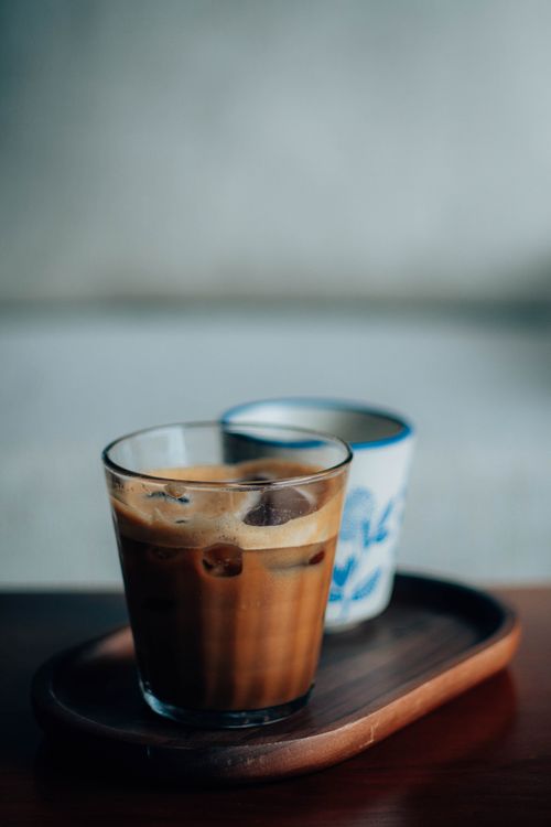 Free Close-up of iced coffee in a glass placed on a wooden tray, evoking a cozy and minimalist ambiance. Stock Photo