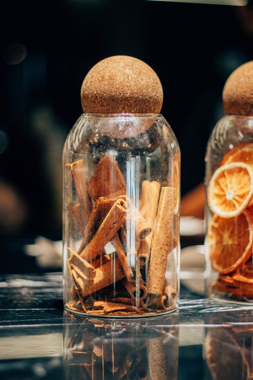 Glass jars with cork ball lids holding cinnamon sticks and dried oranges