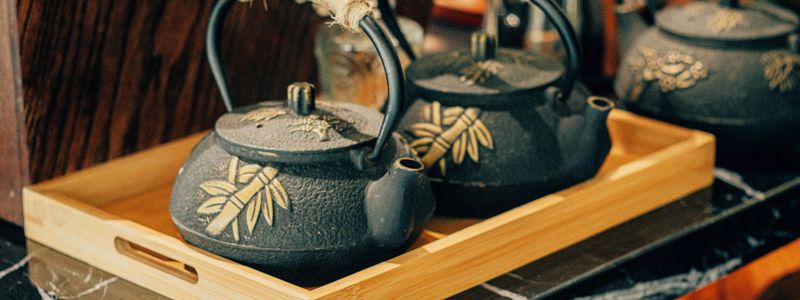 Théières en fonte japonaises posées sur un plateau en bambou — comparatif émaillée et non émaillée