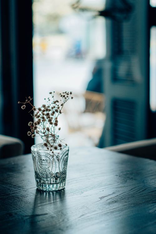 Free A delicate arrangement of dried flowers in a glass vase, set on a wooden table indoors. Stock Photo