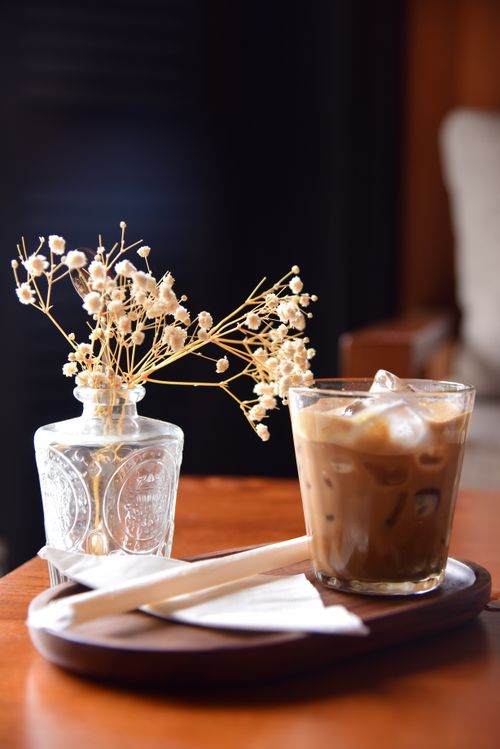 Free Stylish wooden table setting with iced coffee and decorative dried flowers in a cafe. Stock Photo
