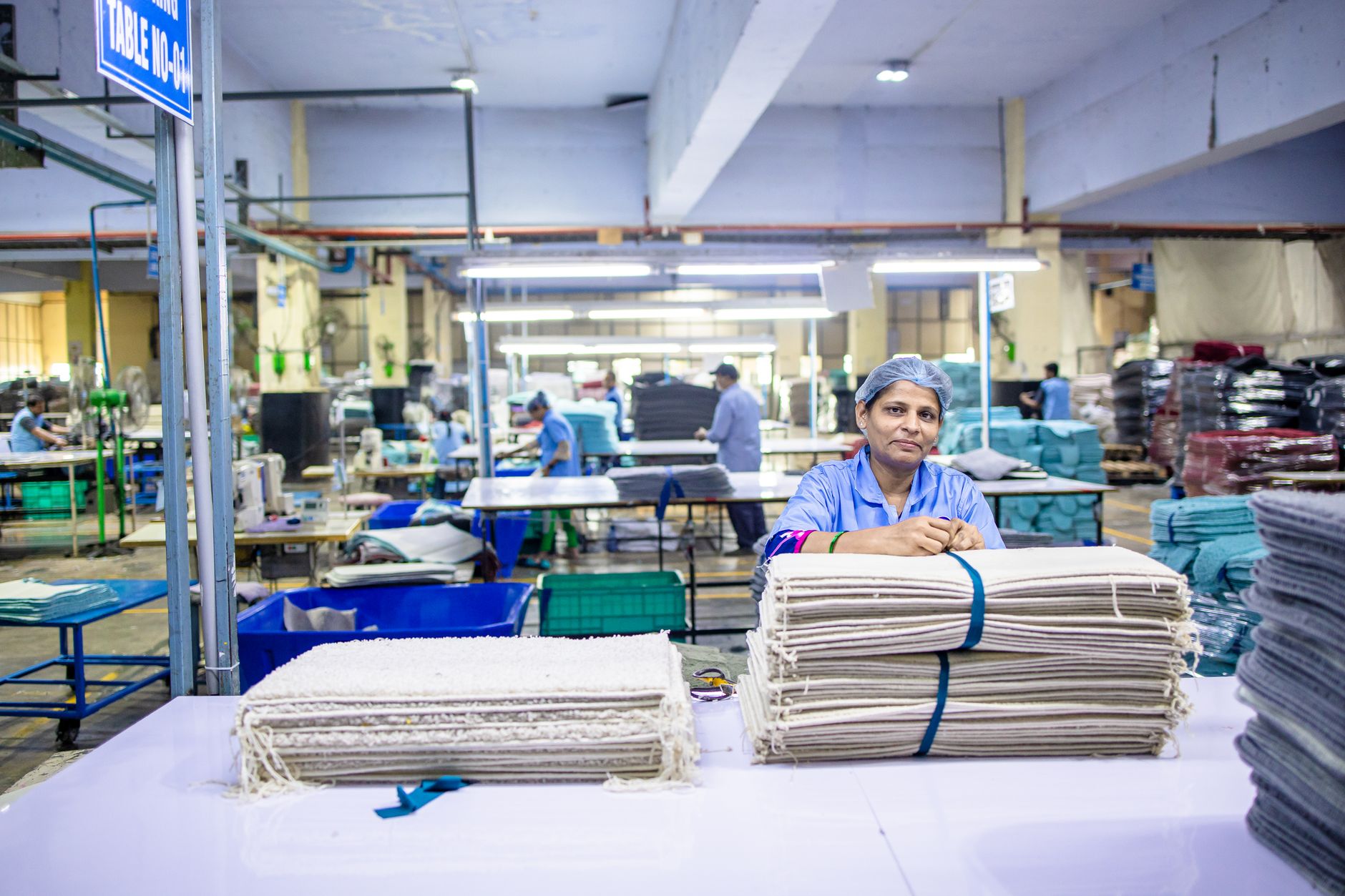 Female worker organizing textile bundles in an industrial factory setting, showcasing blue-collar labor.