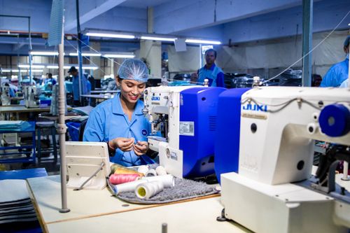 Free Workers in a textile factory operating sewing machines, showcasing blue collar work. Stock Photo