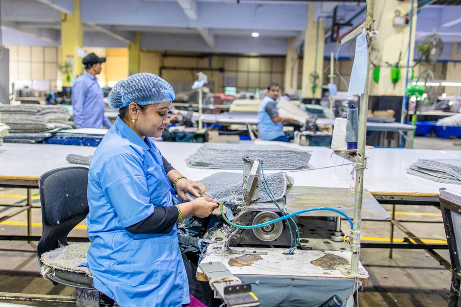 Una trabajadora en un entorno de fábrica utilizando una máquina de coser para la producción textil.