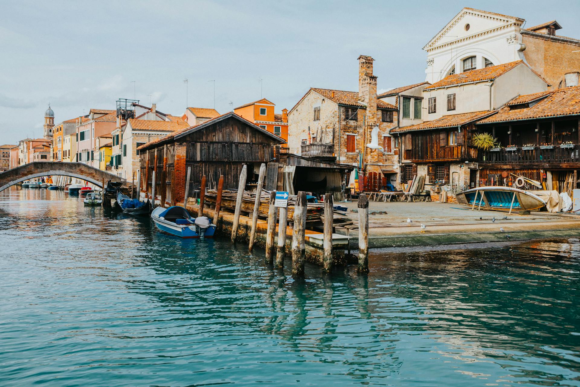 Charming Venetian canal scene with wooden boatyard and historic architecture.