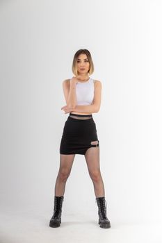 Confident model posing in a chic black skirt and boots, showcasing modern fashion.